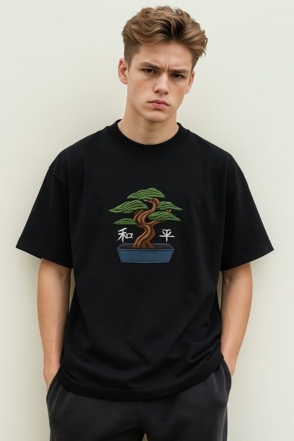 Man wearing a men's green embroidered oversized t-shirt with a bonsai tree design.