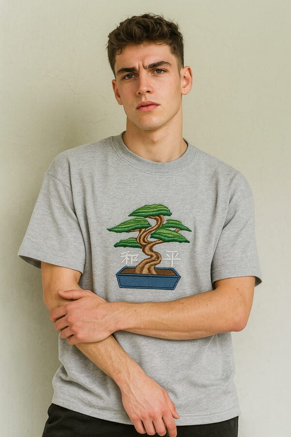 Man wearing a men's grey embroidered oversized t-shirt with a bonsai tree design.