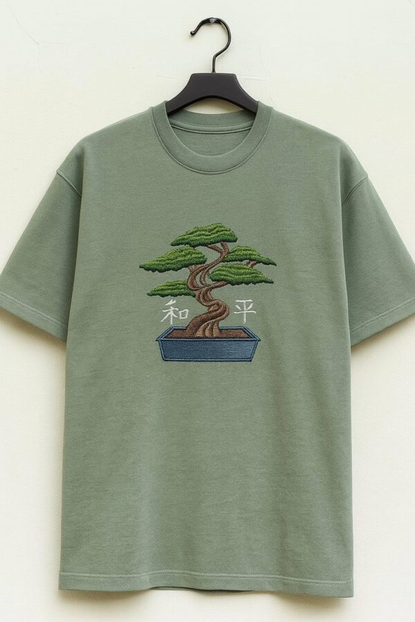 Man wearing a men's green embroidered oversized t-shirt with a bonsai tree design.